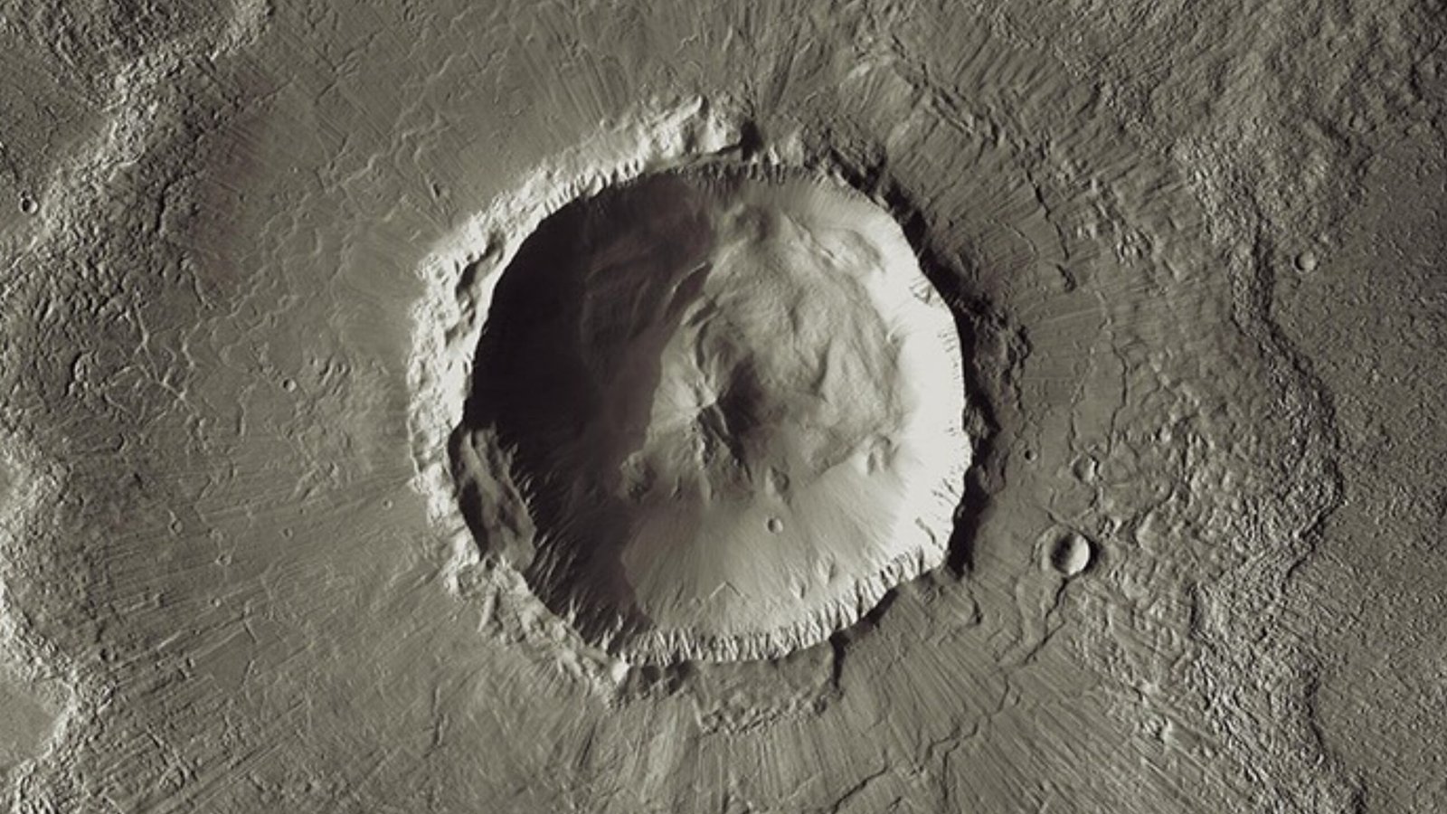 An overhead view of a circular crater and the surrounding textured terrain on Mars.